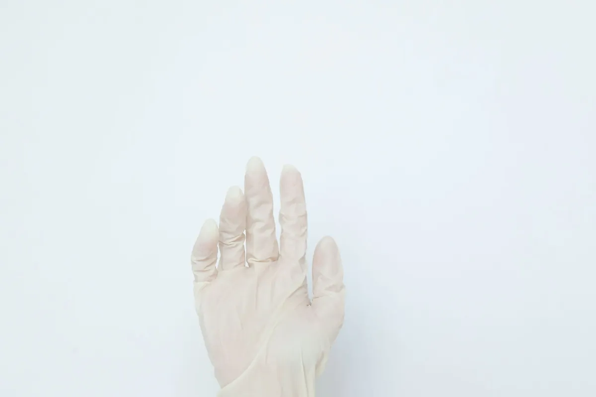 Hands pulling on a white disposable glove